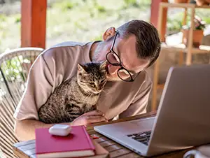 Junger Mann arbeitet zuhause und betreut seine Katze