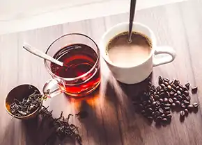 eine Tasse Kaffee neben einer Tasse schwarzem Tee